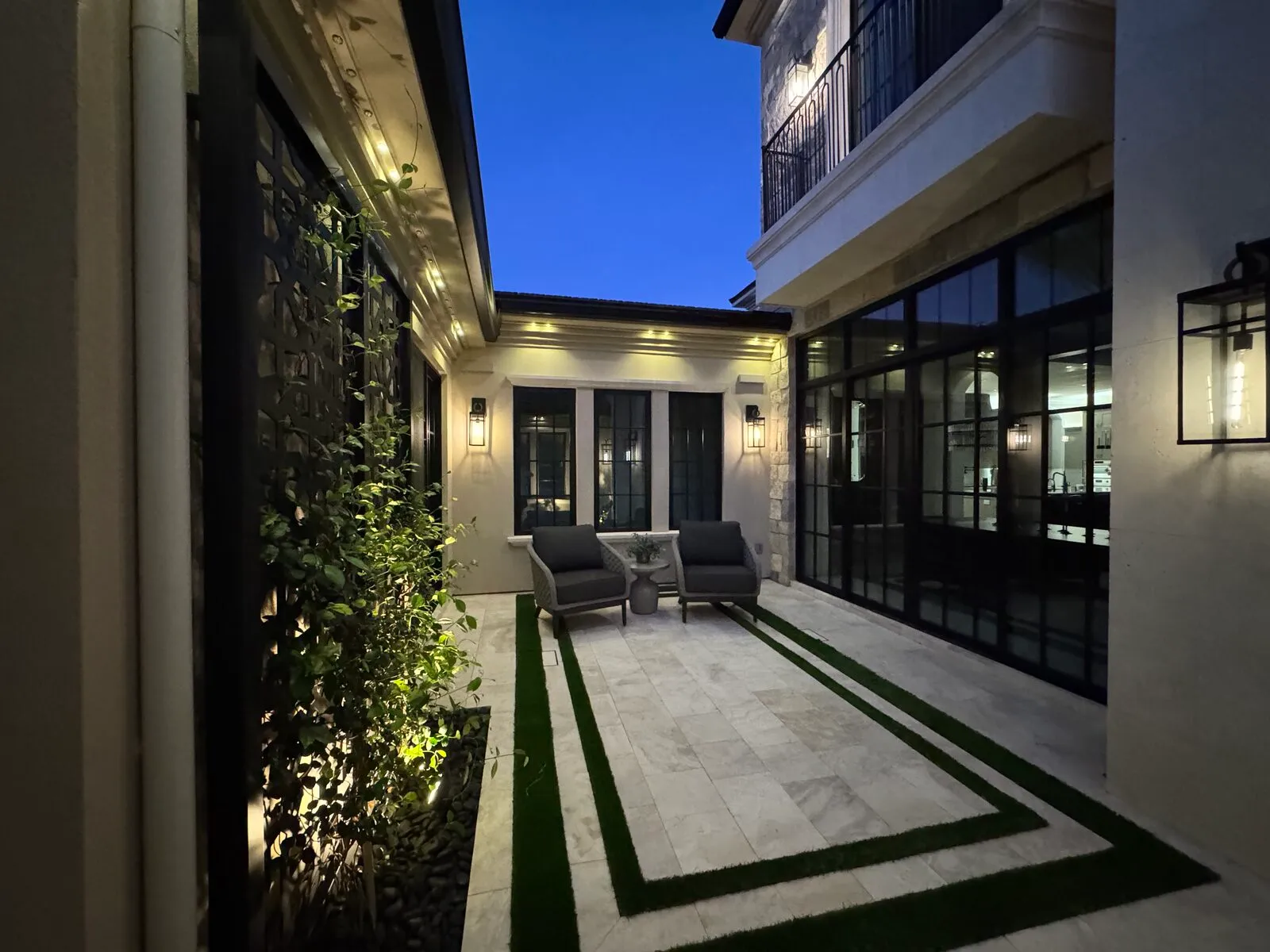 Private courtyard at dusk with floor-to-ceiling glass cleaned to an invisible finish