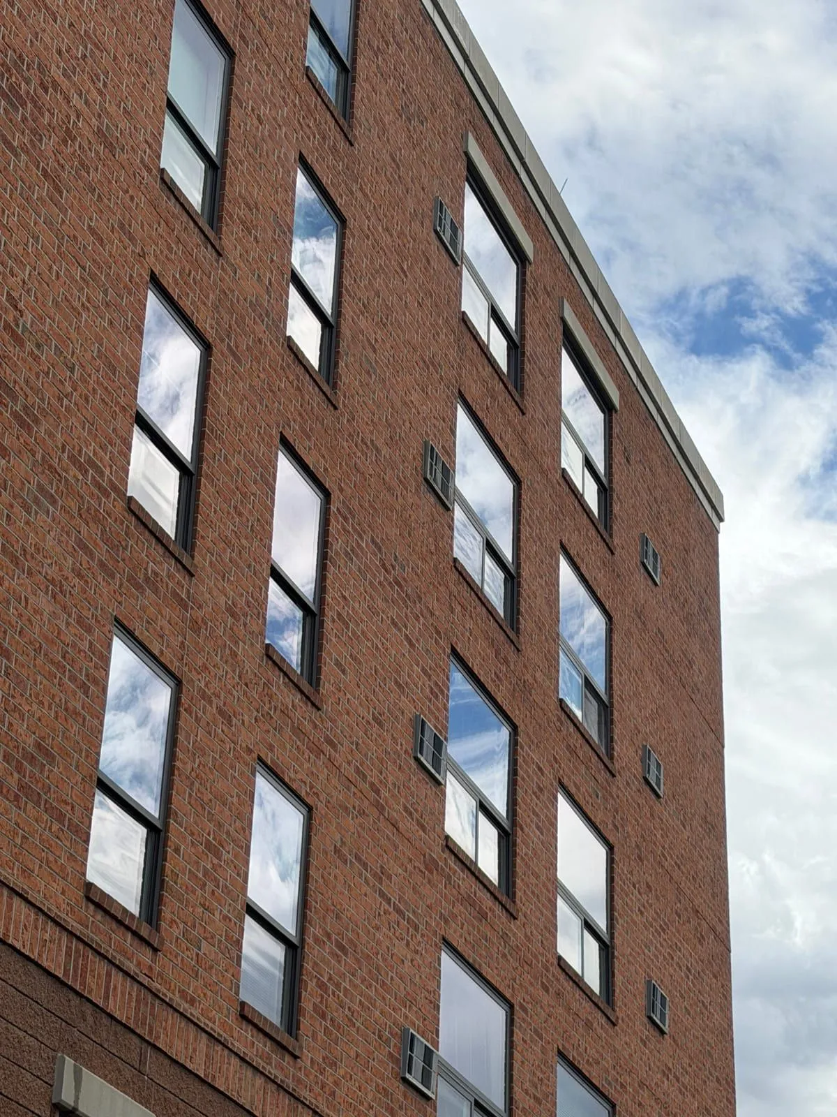 Clean windows reflecting blue sky and clouds on a multi-story brick commercial building in Denver