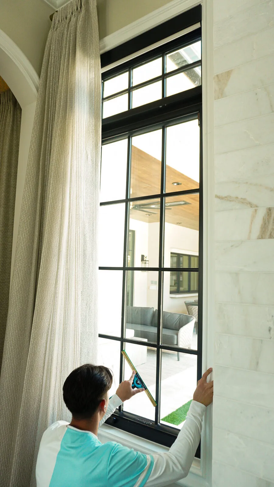 BlueSky technician squeegeeing a tall multi-pane interior window
