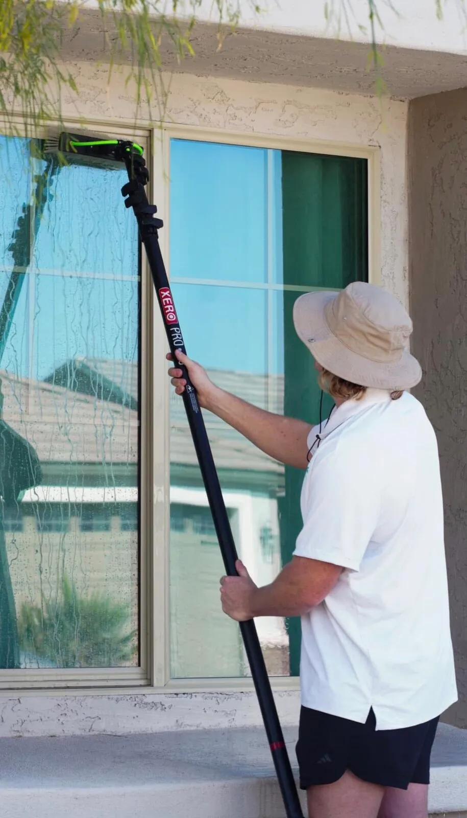 BlueSky technician cleaning upper windows with a water-fed pole from the ground