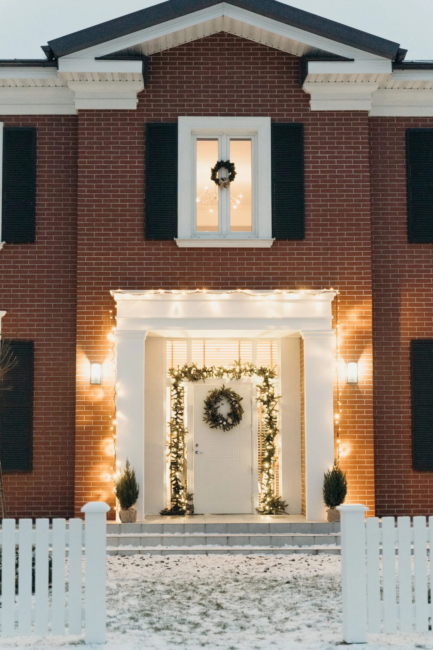 Brick home entrance framed with warm white seasonal lights