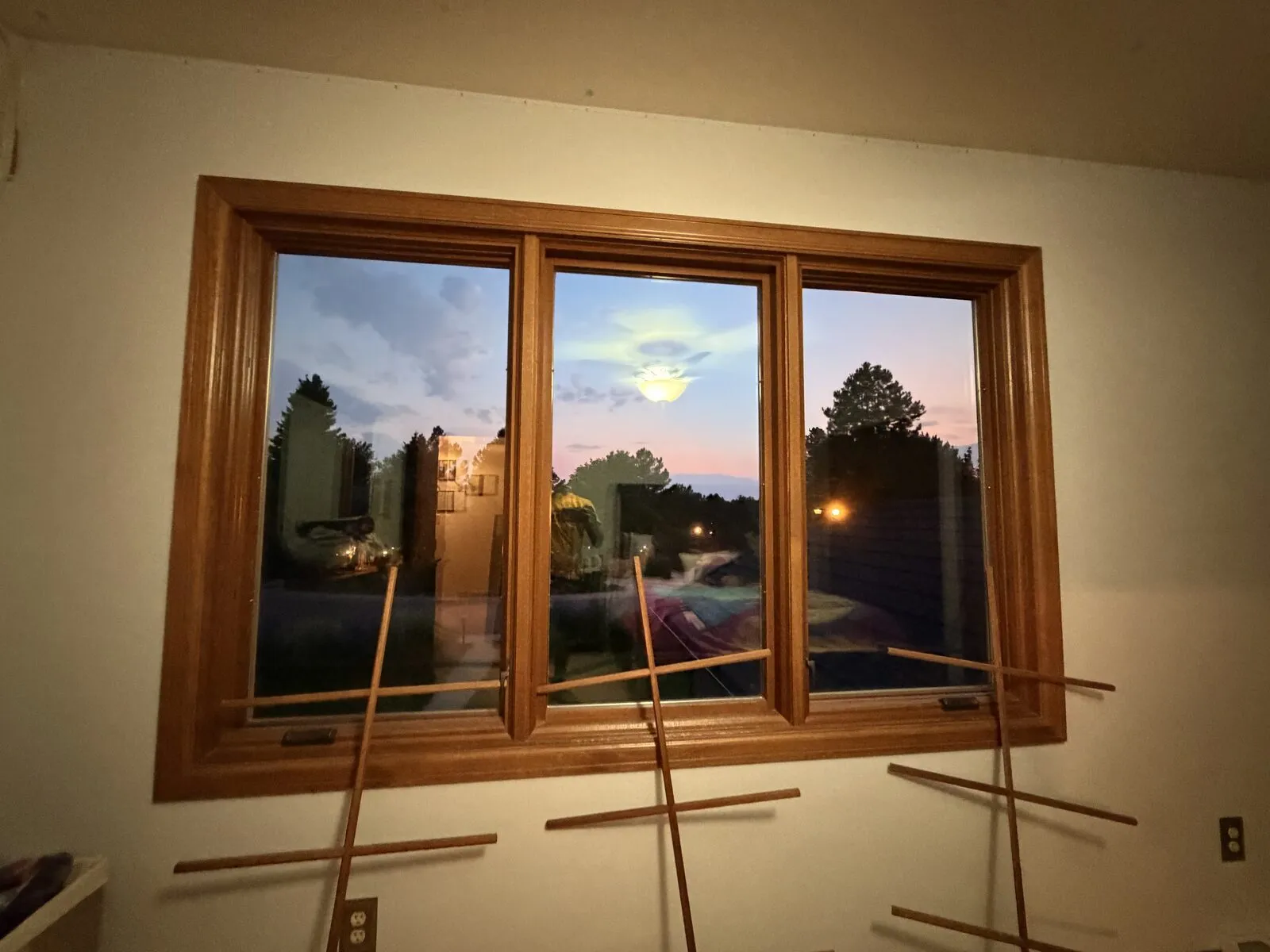 Interior view of a freshly cleaned three-pane wood-trimmed window at dusk in a Castle Rock, Colorado home after residential window cleaning
