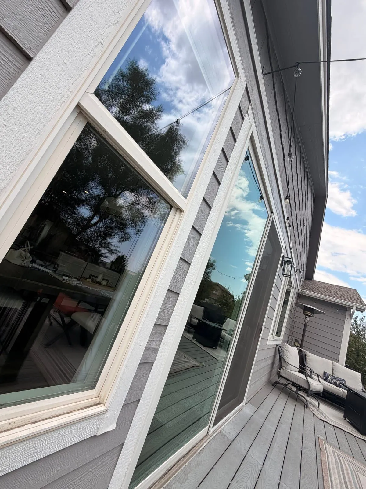 Freshly cleaned tall windows and sliding door reflecting the sky on a Colorado Springs deck