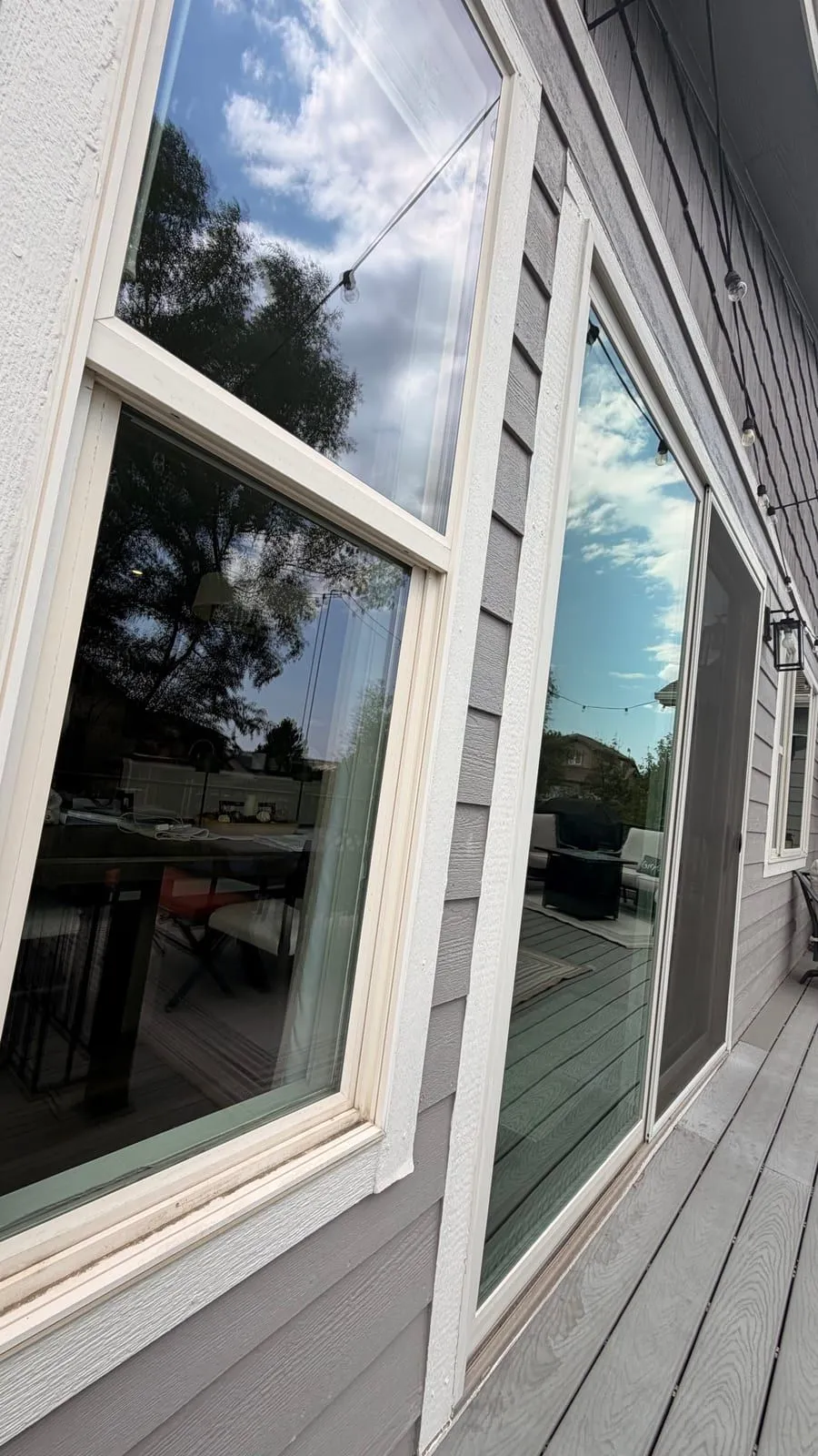 Freshly cleaned double-hung window and sliding door on a Colorado Springs deck with string lights