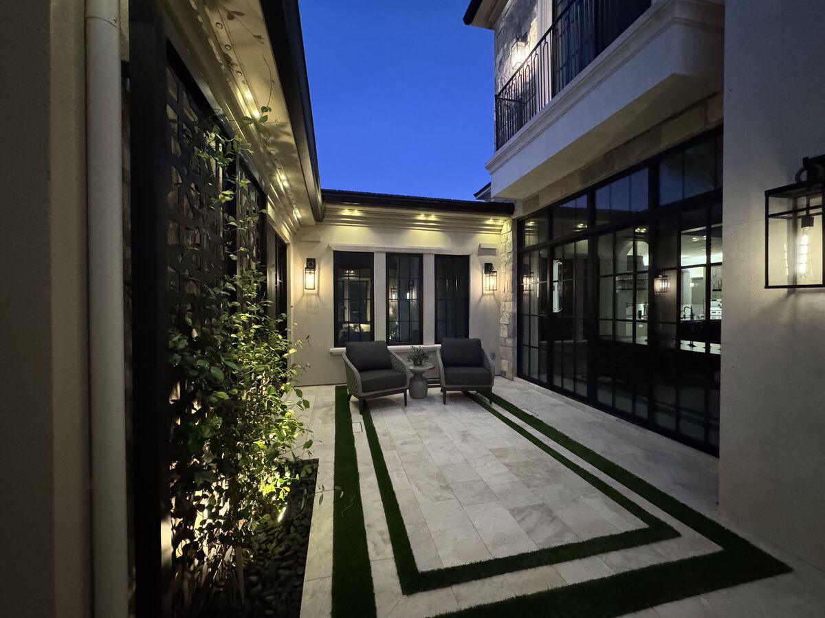 Private courtyard at dusk with floor-to-ceiling glass cleaned to a clear finish